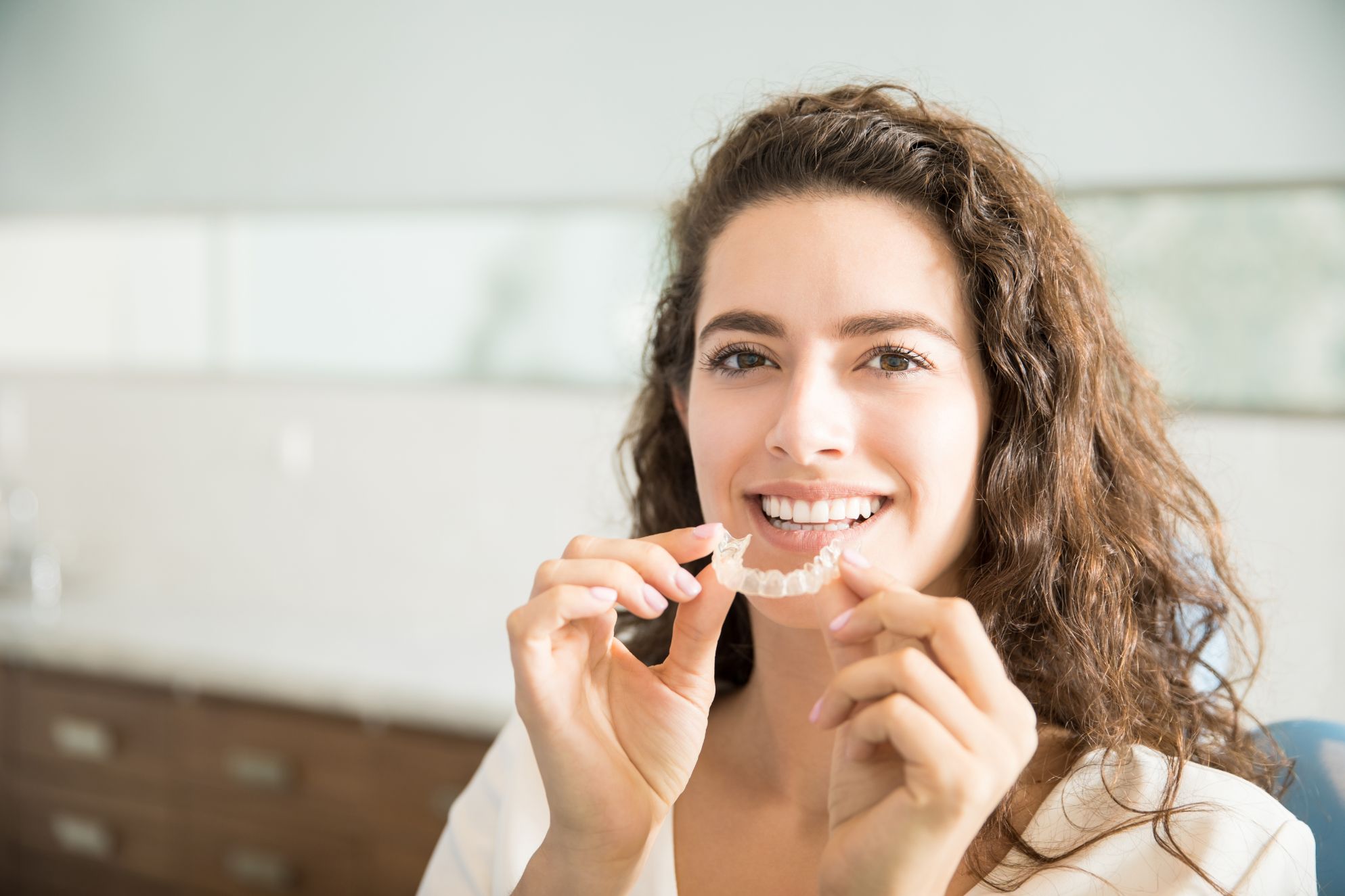 woman holding Invisalign retainers